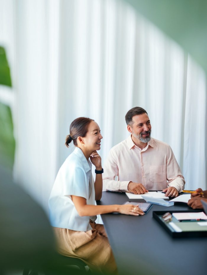 Two coworkers interacting during a workplace meeting, displaying teamwork and camaraderie in a professional setting with a bright, positive atmosphere.